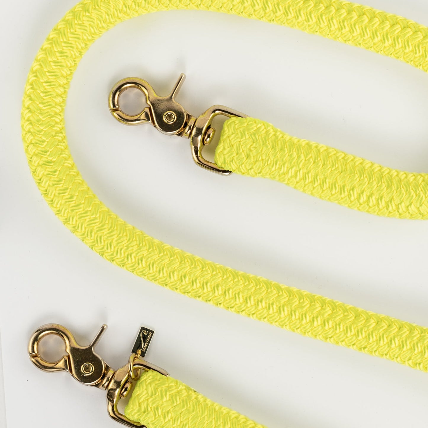 Neon yellow bag straps with gold clasp on a white background